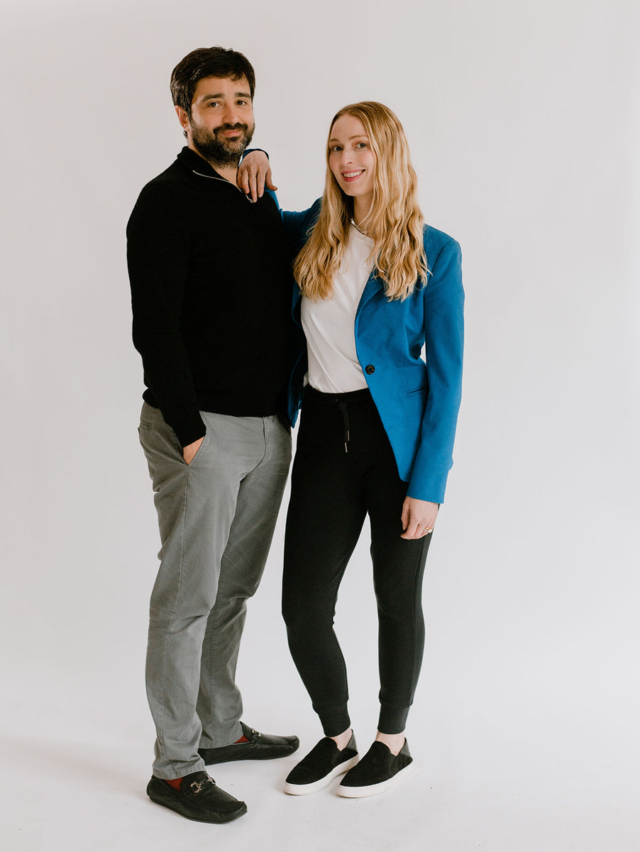 Photo of amrêve co-founders, Nicole and Dany. Dany is wearing a black sweater and gray pants. Nicole is wearing a white shirt, blue blazer, and black joggers. They are looking at the camera and smiling.