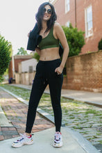 Load image into Gallery viewer, Photo of a woman wearing amrêve organic pima cotton joggers in black and organic pima cotton bralette in chive.