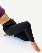 Load image into Gallery viewer, Photo of a woman wearing amrêve organic pima cotton joggers in black and organic pima cotton bralette in blackberry wine.