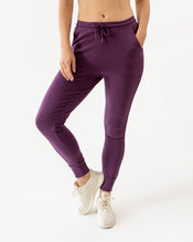 Load image into Gallery viewer, Photo of a woman from the waist down wearing amrêve organic pima cotton joggers in blackberry wine purple.
