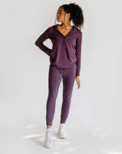 Load image into Gallery viewer, A woman is standing with one hand on her hip in the matching amrêve purple organic hoodie and jogger set.
