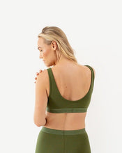 Load image into Gallery viewer, A woman is wearing the amrêve organic cotton bralette in green. She is looking over her shoulder to show the scoop neck back.
